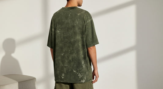 Person wearing a green t-shirt against a white wall