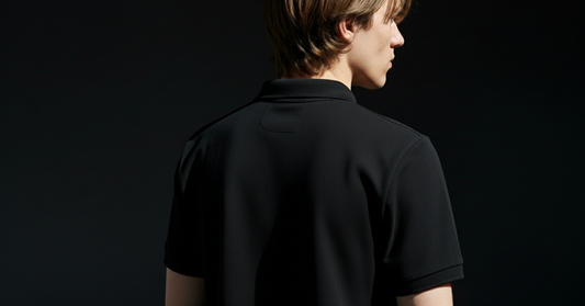Person wearing a black polo shirt against a black background