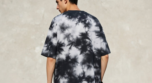 Person wearing a black and white tie-dye t-shirt against a plain background