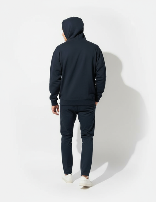 Person wearing a navy blue hoodie and pants on a white background