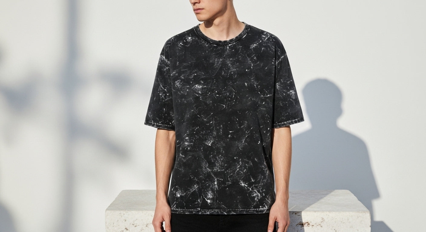 Person wearing a black acid-washed t-shirt against a light background