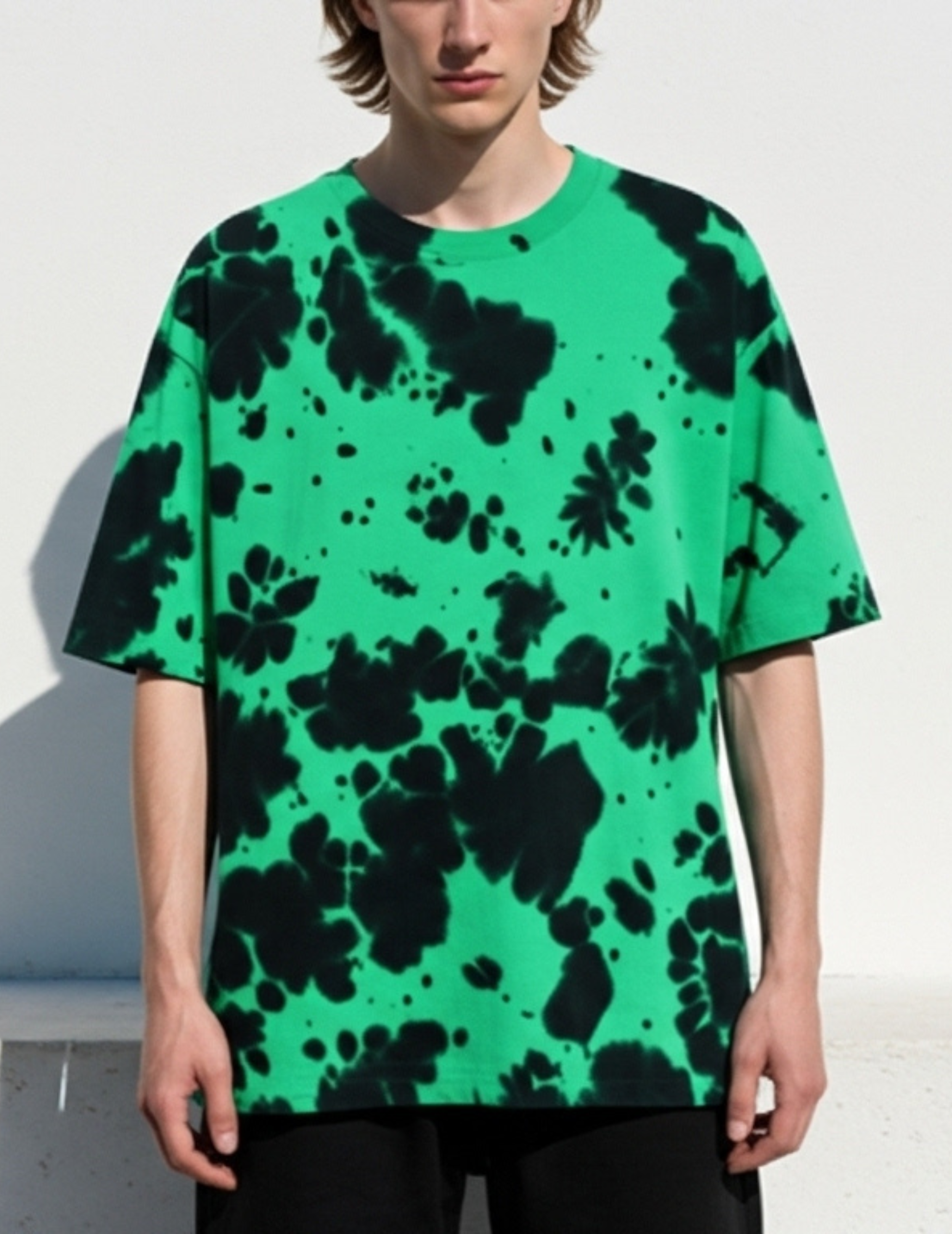 Person wearing a green t-shirt with black abstract pattern against a white background