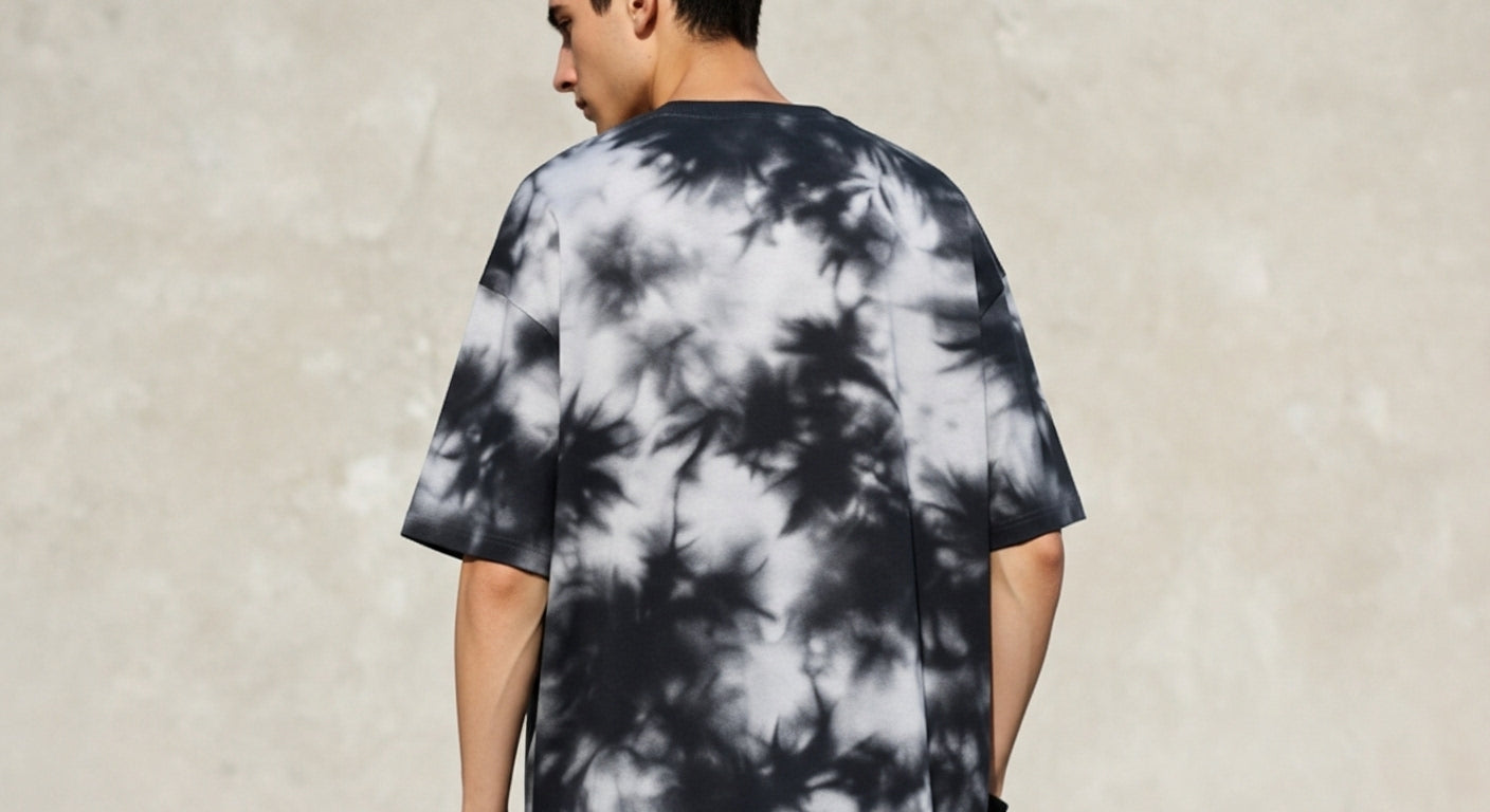 Person wearing a black and white tie-dye t-shirt against a plain background