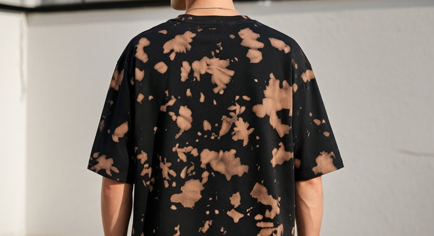 Black t-shirt with brown abstract patterns worn by a person against a plain background