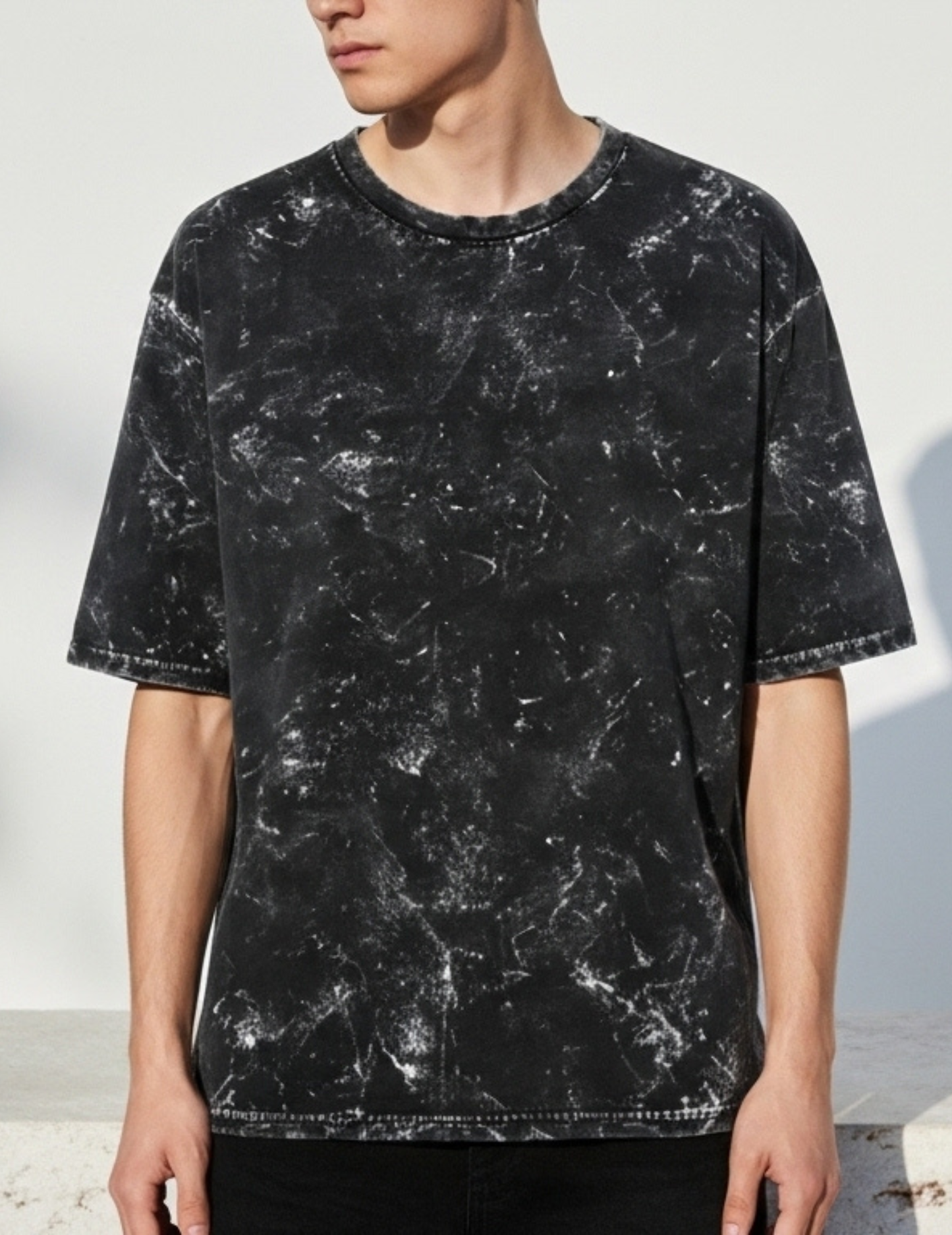 Person wearing a black marble-textured t-shirt against a white background