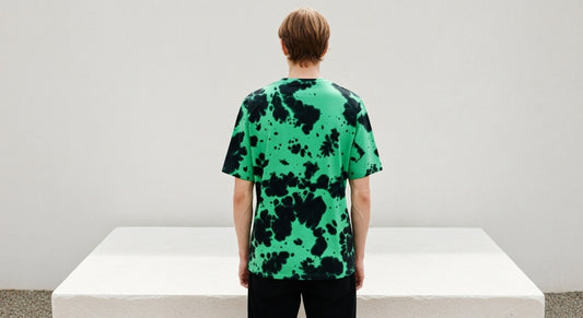 Person wearing a green and black patterned shirt standing on a white platform with a plain background