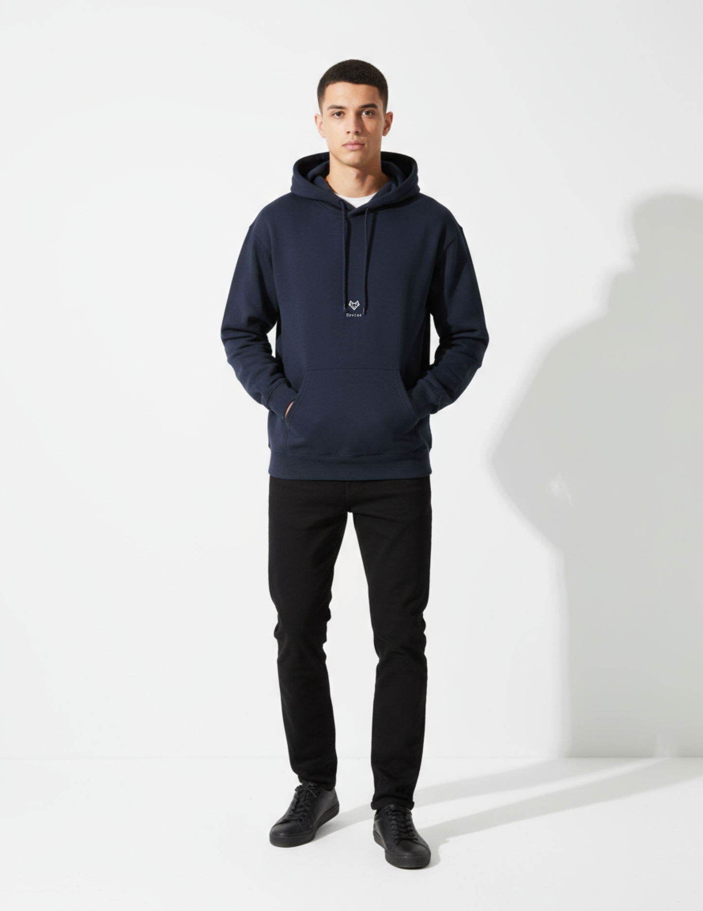 Man wearing a navy hoodie and black pants on a white background