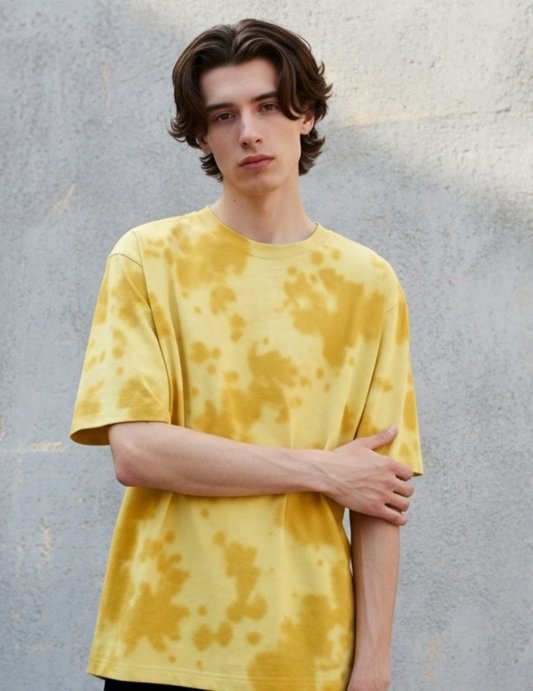 Person wearing a yellow tie-dye shirt against a gray background